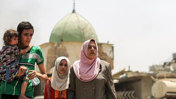 KEMENANGAN IRAK ATAS ISIS Iraqis flee from the Old City of Mosul, with the destroyed Al-Nuri Mosque seen in the background, on July 2, 2017, as Iraqi government forces continue their offensive to retake the city from Islamic State (IS) group fighters.Explosions on the evening of June 21, 2017 levelled the mosque where Abu Bakr al-Baghdadi gave his first sermon as leader of the Islamic State group, along with its ancient minaret. / AFP PHOTO / AHMAD AL-RUBAYE