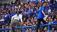 Dua orang pendukung Persib memberikan komando dari atas pagar pembatas tribun.