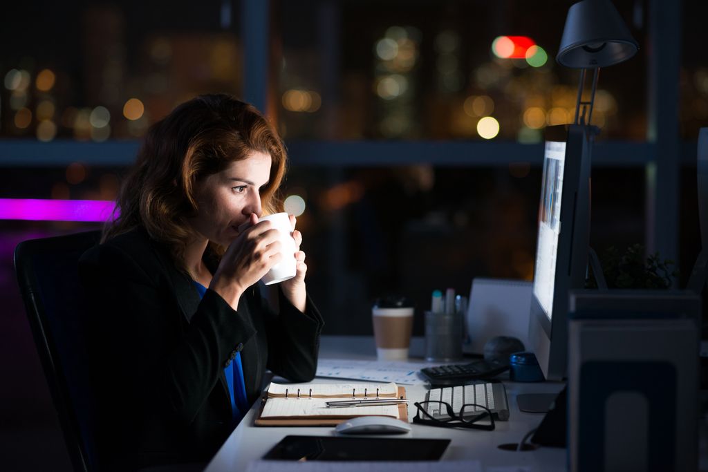 Business woman drinking coffee to get some energy for working overtime