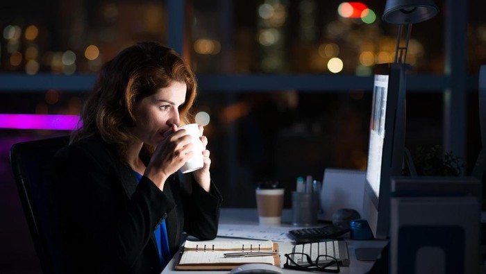 502284198 Business woman drinking coffee to get some energy for working overtime