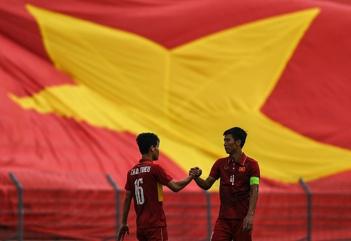 Vietnams Bui Tien Dung (R) and Tran Huu Dong Trieu shake hands in front of their countrys flag after their winning their mens football Group B round match against East Timor at the 29th Southeast Asian Games (SEA Games) at Selayang Stadium, outside Kuala Lumpur on August 15, 2017. / AFP PHOTO / Mohd RASFAN        (Photo credit should read MOHD RASFAN/AFP/Getty Images)