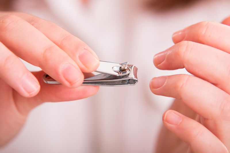 Mid adult woman sitting and cutting her fingernails