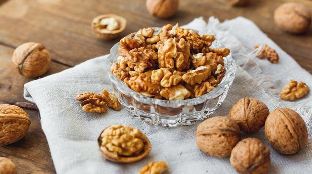 Walnuts with wooden spoon on background
