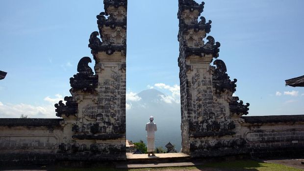 Pemuka Agama Hindu berjalan di Pura Lempuyang dengan latar Gunung Agung di Karangasem, Bali, Rabu (27/9). Berdasarkan data Pusat Vulkanologi dan Mitigasi Bencana Geologi aktvitas Gunung Agung masih tetap tinggi sehingga seluruh warga di area radius sembilan kilometer dari kawah gunung dan ditambah perluasan sektoral ke arah Utara, Timur laut, Tenggara, Selatan dan Barat Daya sejauh 12 km direkomendasikan untuk mengungsi. ANTARA FOTO/Wira Suryantala/nym/foc/17.