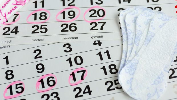 Woman protecting health , menstruation days , laying on a calendar with the selected days