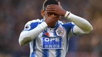 Jersey kandang Huddersfield sepantasnya masuk ke daftar seragam terburuk musim 2017/2018. Kombinasi garis vertikal dengan gradasi plus papan sponsor yang besar bukanlah ide yang bagus. Pemainnya saja tak mau melihat tuh. (Foto: Gareth Copley/Getty Images)