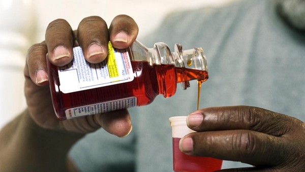Senior man pouring medicine out of bottle, close-up