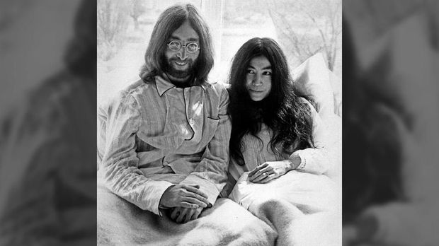 Beatles member John Lennon (L) and his wife Yoko Ono receive journalists 25 March 1969 in the bedroom of the Hilton hotel suite in Amsterdam, during their honeymoon in Europe. / AFP PHOTO / ANP / FILES