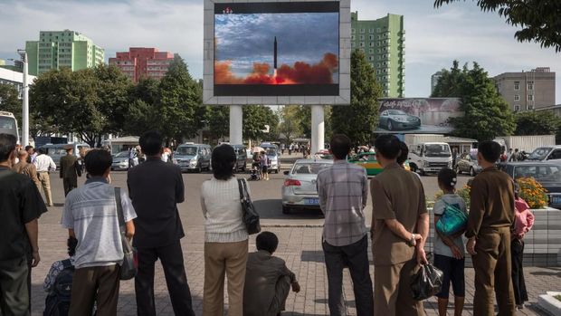 People watch as a screen shows footage of the launch of a Hwasong-12 rocket, beside a billboard advertising North Korea's Pyeonghwa Motors (R), in Pyongyang on September 16, 2017.
North Korea said on September 16 it was seeking military 