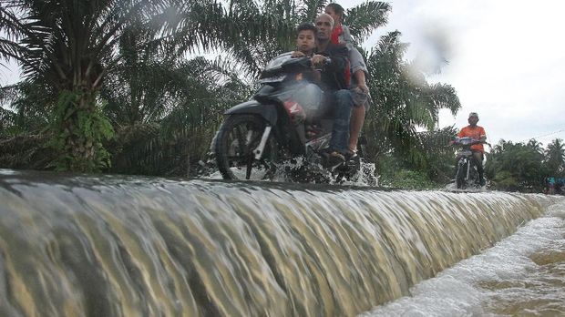 Warga melintasi banjir di Desa Lhok Sentang, Julok, Aceh Timur, Aceh, Selasa (5/12). Tingginya curah hujan sejak dua pekan terakhir membuat sungai Arakundo meluap dan merendam ratusan rumah warga serta ratusan hektar lahan pertanian, tambak ikan warga, perkebunan dengan ketinggian air 50 sampai 150 cm. ANTARA FOTO/Syifa Yulinnas/foc/17.