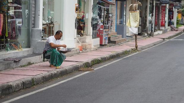 BALI, INDONESIA – 4 DESEMBER: Seekor pria merapikan sesajen di tepi jalanan Ubud, Bali, yang kini lengang pada 4 Desember 2017. Badan Pusat Statistik menyatakan, kunjungan wisatawan mancanegara melalui Bandara Internasional I Gusti Ngurah Rai Denpasar pada November 2017 turun 16 persen dari bulan sebelumnya, dikarenakan aktivitas vulkanik Gunung Agung.  ( Mahendra Moonstar - Anadolu Agency )