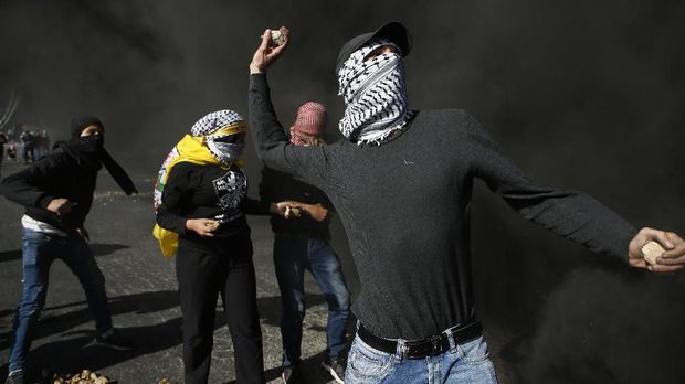 JALUR GAZA MEMANAS A Palestinian protestor throws stones towards Israeli security forces during clashes in the West Bank city of Ramallah on December 11, 2017 as demonstrations continue to flare in the Middle East and elsewhere over US President Donald Trump's declaration of Jerusalem as Israel's capital. / AFP PHOTO / ABBAS MOMANI