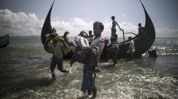 A Bangladeshi man helps Rohingya Muslim refugees to disembark from a boat on the Bangladeshi shoreline of the Naf river after crossing the border from Myanmar in Teknaf on September 30, 2017.More than 2,000 Rohingya have massed along Myanmar's coast this week after trekking from inland villages in Rakhine state to join the refugee exodus to Bangladesh, state media reported September 30. They follow more than half a million fellow Rohingya who have emptied out of northern Rakhine in a single month, fleeing an army crackdown and communal violence the UN says amounts to 