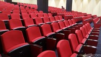 Deretan kursi merah untuk para pewarta ditata berundak sedemikian rupa seperti halnya di bioskop, dengan meja panjang dan sejumlah kursi diposisikan di tengah bawah.
