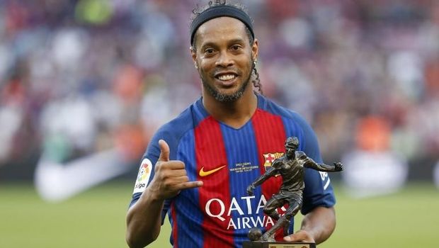 Former Barcelona's Brazilian forward Ronaldinho poses with the trophy for the best player after a charity football match between Barcelona Legends vs Manchester United Legends at the Camp Nou stadium in Barcelona on June 30, 2017. / AFP PHOTO / Pau Barrena