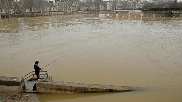 Foto: Paris Banjir, Pria Ini Malah Asyik Memancing di Sungai Seine