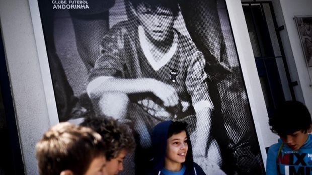 Seorang pesepakbola muda berpose di depan poster Cristiano Ronaldo yang dipajang di stadion milik FC Andorinha.
