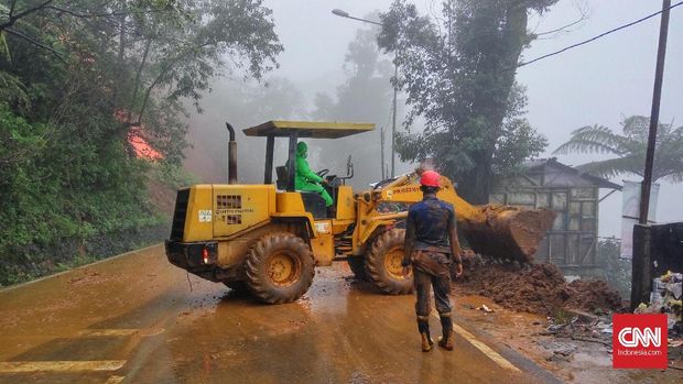 Alat berat membantu menyingkirkan tanah longsor dari jalanan, di Puncak, Bogor, Selasa (6/2). 