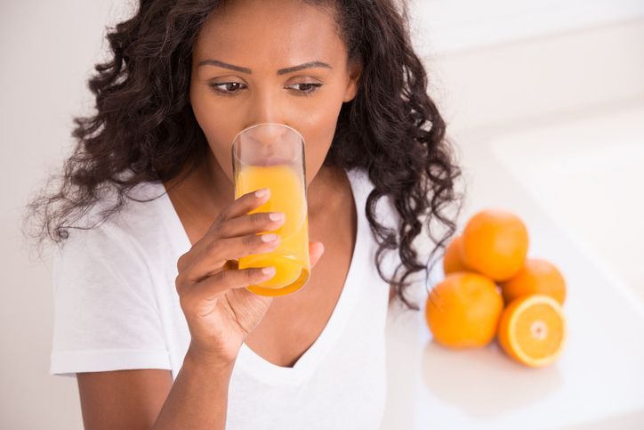 Thirsty woman drinking fresh orange juice at kitchen (high angle view).