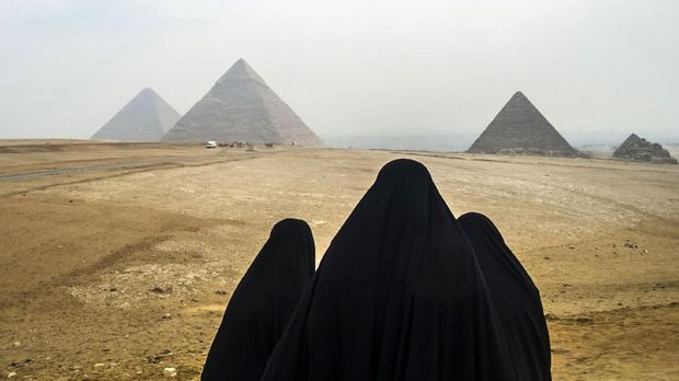 Female tourists wearing veils look at the Pyramids of Giza as they stand from across the Giza plateau, on the southwestern outskirts of the Egyptian capital Cairo on February 15, 2018. / AFP PHOTO / KHALED DESOUKI