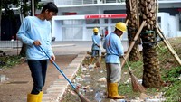 Petugas tampak menyapu sampah-sampah yang memenuhi taman.