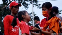 Seorang ibu tengah memakaikan jersey Persija kepada putrinya jelang laga Piala AFC.