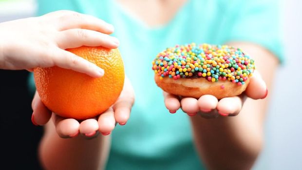 Educate children to choose healthy food concept with little girl choice to eat fruit, not a donut