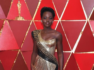 Lupita Nyongo tetap memancarkan pesona dan aura seksi kala tampil dengan gaun warna emas. Kevork Djansezian/Getty Images.