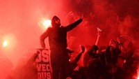 Begini salah satu aksi para pendukung PSG di tribune. Sinar flare merah menyala menjadi latarnya. (Foto: Franck Fife/AFP)