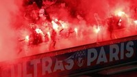 Ultras Paris berjejer di pembatas tribune sambil menyalakan flare. Tribune belakang gawang menjadi titiknya. (Foto: Pierre-Philippe Marcou/AFP)