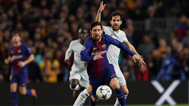 Lionel Messi melakukan trik di lapangan yang membuat Cesc Fabregas terjatuh
