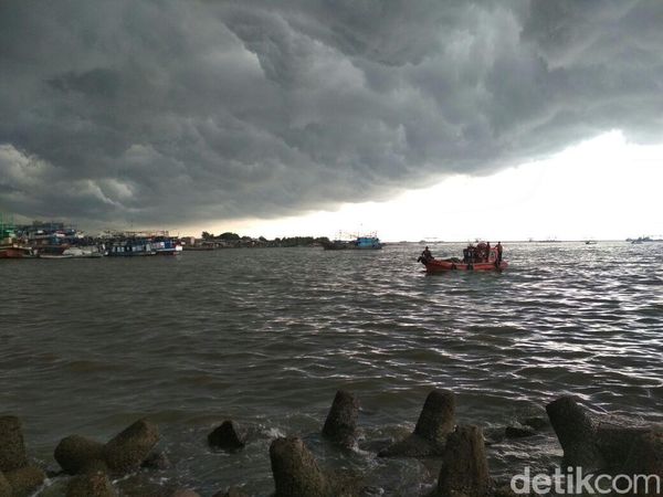 Awan Gelap Payungi Petugas Bersihkan Lautan Sampah di Teluk Jakarta