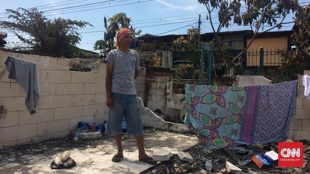 Adi tengah melihat puing-puing sisa rumahnya yang terbakar.