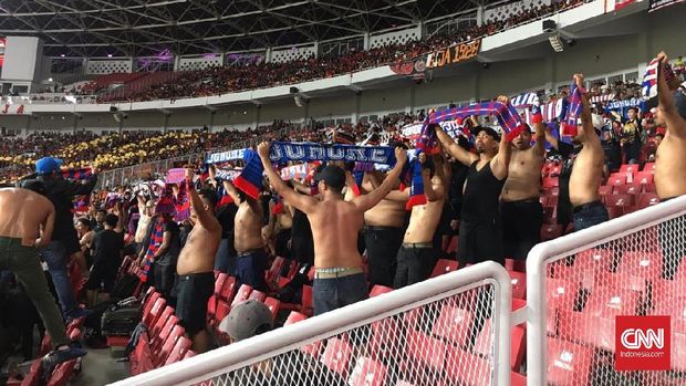 Suporter JDT mendukung timnya sembari berdiri di kursi tribune SUGBK.
