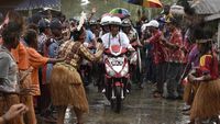 Foto: Jokowi-Iriana Boncengan Motor Menembus Hujan di Asmat