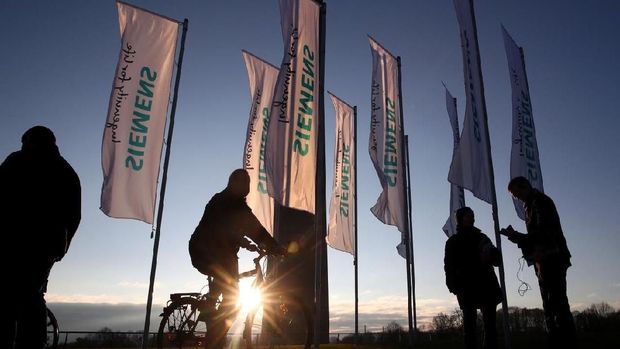 People pass Siemens flags ahead of the company's annual shareholders meeting in Munich, Germany, January 31, 2018. REUTERS/Michael Dalder