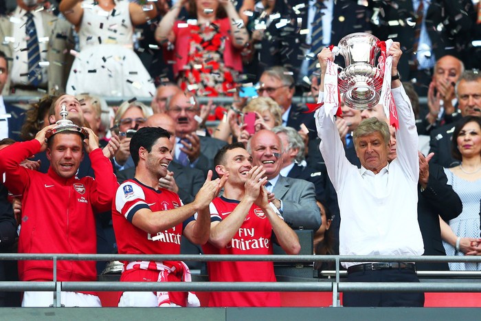 LONDON, ENGLAND - MAY 17:  Arsene Wenger manager of Arsenal (R) lifts the trophy in celebration alongside Lukas Podolski (L), Mikel Arteta (2L) and Thomas Vermaelen (2R) after the FA Cup with Budweiser Final match between Arsenal and Hull City at Wembley Stadium on May 17, 2014 in London, England.  (Photo by Clive Mason/Getty Images)