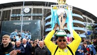 Ada juga yang membawa replika trofi Premier League, yang sebenarnya baru akan didapat City pada laga kandang terakhir mereka musim ini. (Clive Brunskill/Getty Images)