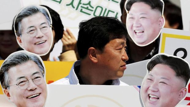 Warga membawa topeng Presiden Korsel Moon Jae-in dan pemimpin Korut Kim Jong-il.
