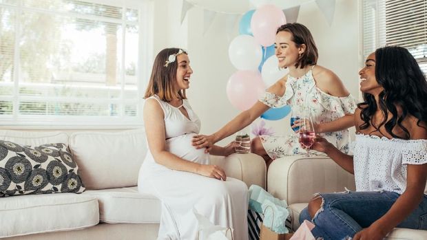 Smiling pregnant woman with female friends at baby shower. Group of female friends meeting for baby shower at home.