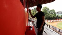 Pekerja tengah mengecat tribun penonton.