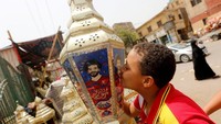 Anak kecil mencium salah satu lampion di mana ada foto Salah. Salah tak pelak dewa baru untuk warga Mesir saat ini. (Amr Abdallah Dalsh/Reuters)