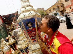 Anak kecil mencium salah satu lampion di mana ada foto Salah. Salah tak pelak dewa baru untuk warga Mesir saat ini. (Amr Abdallah Dalsh/Reuters)