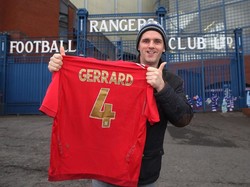 Kabar Gerrard bakal menjadi manajer Rangers sudah diketahui para fans. Derek Devin, fans Rangers, langsung berpose di depan Stadion Ibrox dengan membentangkan jersey merah Timnas Inggris bernomor 4 milik Gerrard. (Foto: Ian MacNicol/Getty Images)