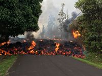 Aliran lava dari gunung berapi Kilauea, bergerak di jalan di Leilani Estates di Hawaii, Minggu (6/5/2018)