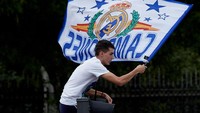 Salah satu fans tampak naik ke lampu lalu lintas untuk bisa melihat dengan jelas skuat Real Madrid. (Foto: Gonzalo Arroyo Moreno/Getty Images)