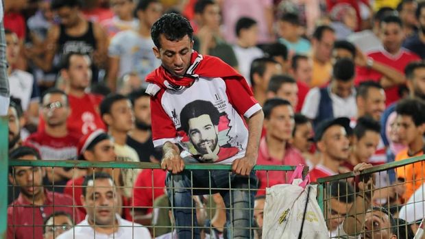 Salah satu pendukung timnas Mesir yang mengenakan kaus bergambar Mohamed Salah memanjat pagar pembatas stadion
