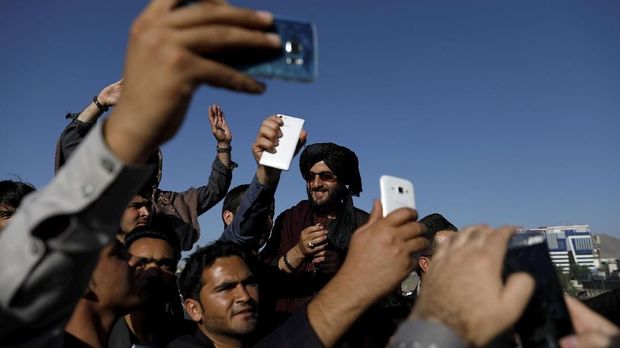 Warga berswafoto dengan Taliban saat gencatan senjata Idulfitri, di Afghanistan, Juni.