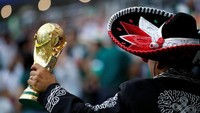 Dengan pede-nya pendukung Meksiko menentang replika tropy piala dunia. REUTERS/Carl Recine.