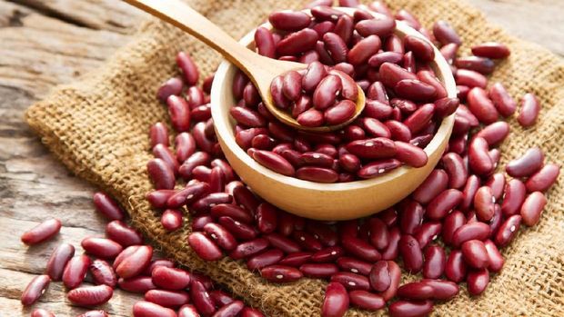 Red bean on wooden bowl with spoon and linen background top view